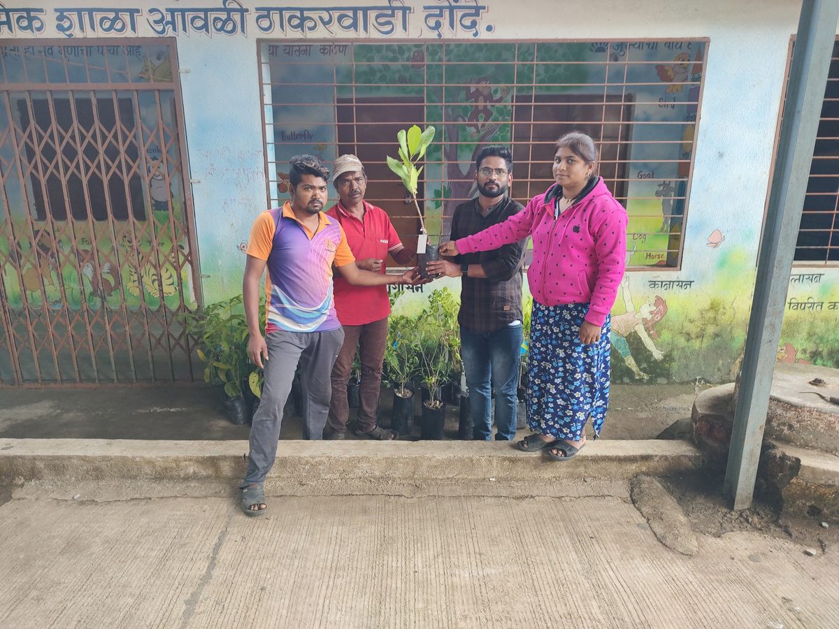 Volunteers handing over a sapling near a village school